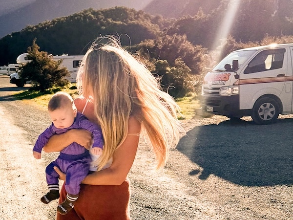 Standing in front of a Campervan Holding an Infant in New Zealand with Mountains