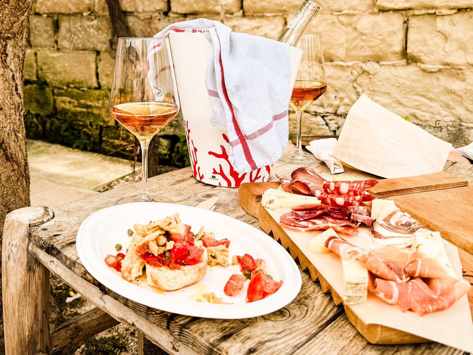 Traditional food of Puglia, Italy, Friselle, with tomato and artichoke with cheese board and orange wine in the terraced garden at L'Ortale Restaurant. 