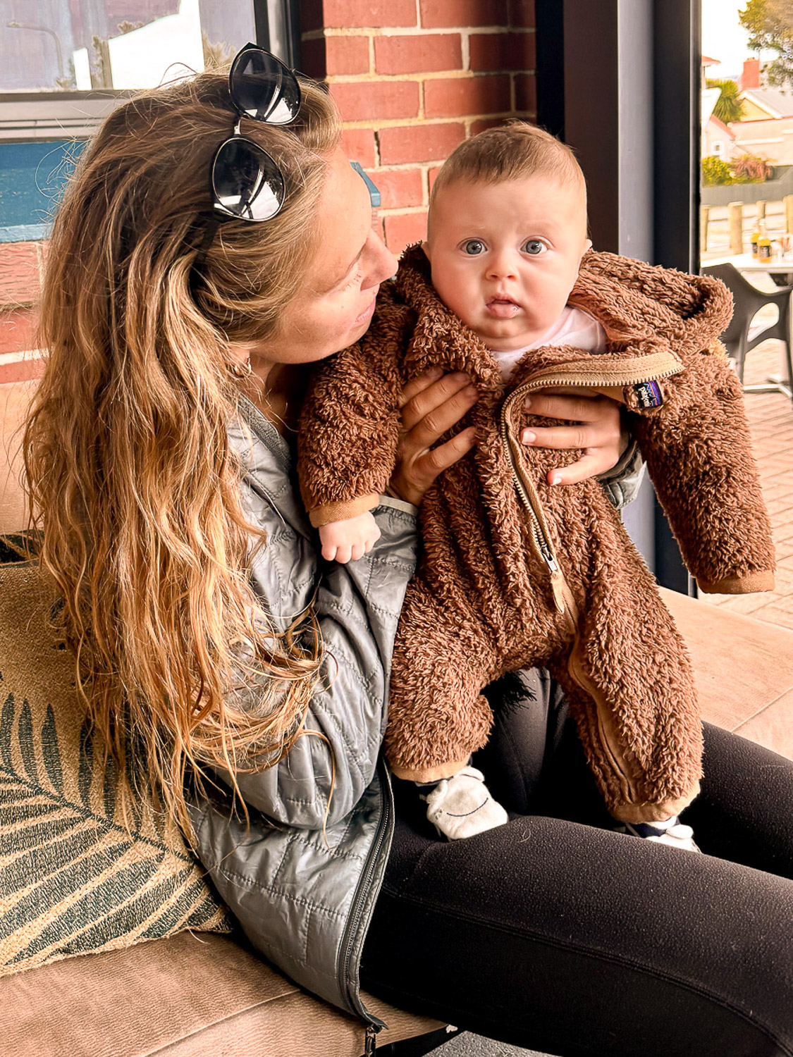 Reasons Travel to New Zealand with a Baby: Mom holding small baby at a restaurant in Dunedin, New Zealand