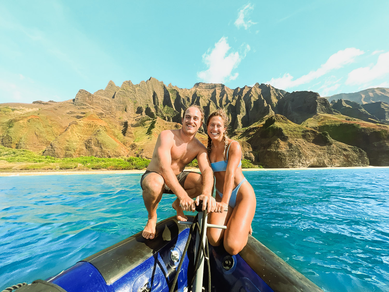 Best things to do in Kauai: Sitting on the bow of a zodiac boat with the Na Pali coast in the background during a Na Pali Coast Boat Tour in Kauai, Hawaii