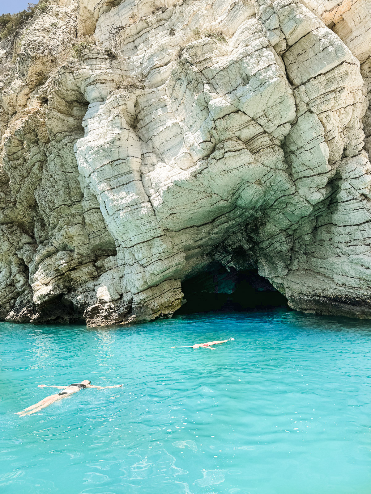 Floating in the water outside of a grotto at Spiaggia di Portopiatto beach during a boat tour in Vieste, Puglia, Italy