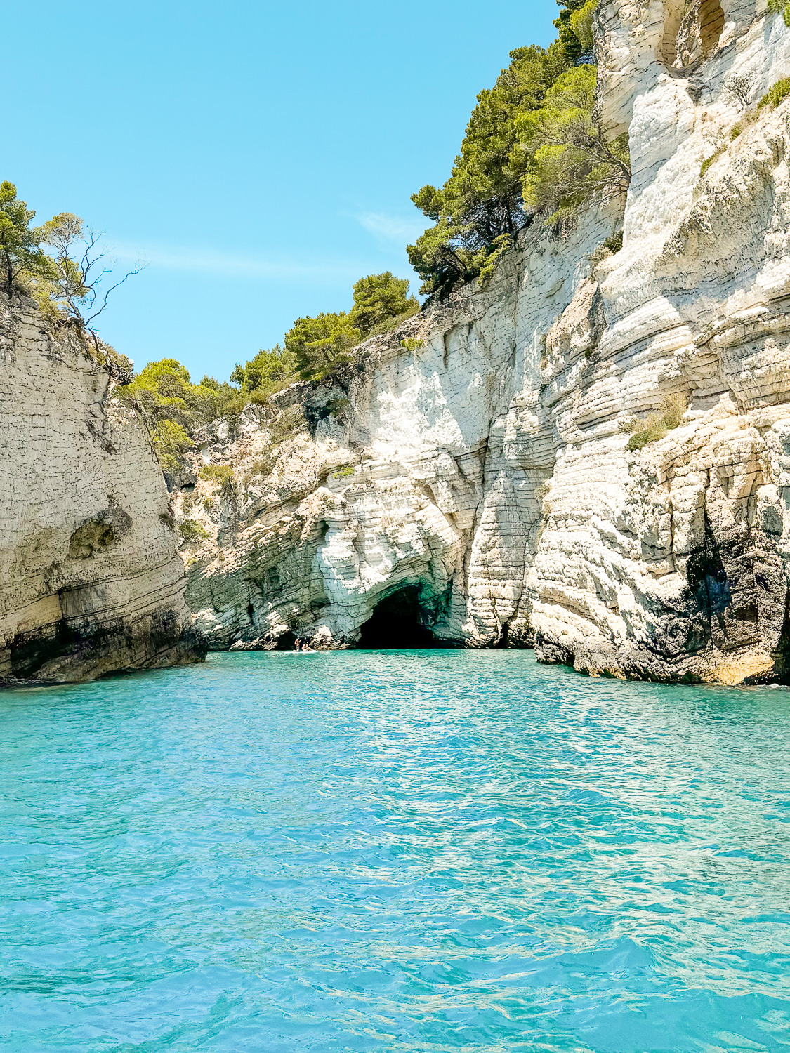Looking at the turquiose water and grotto at Spiaggia di Portopiatto beach during a boat tour in Vieste, Puglia, Italy