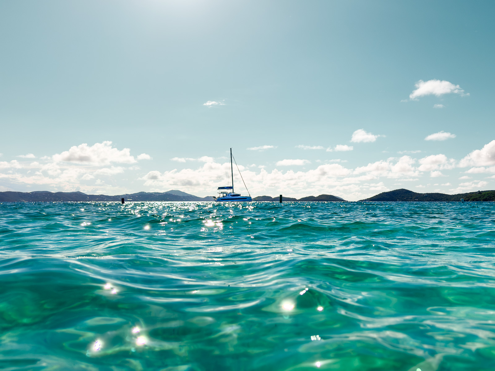 11 Very Best Things to do in St. John: Catamaran Sailboat on Caribbean blue water with mountains in the background in St. John, USVI