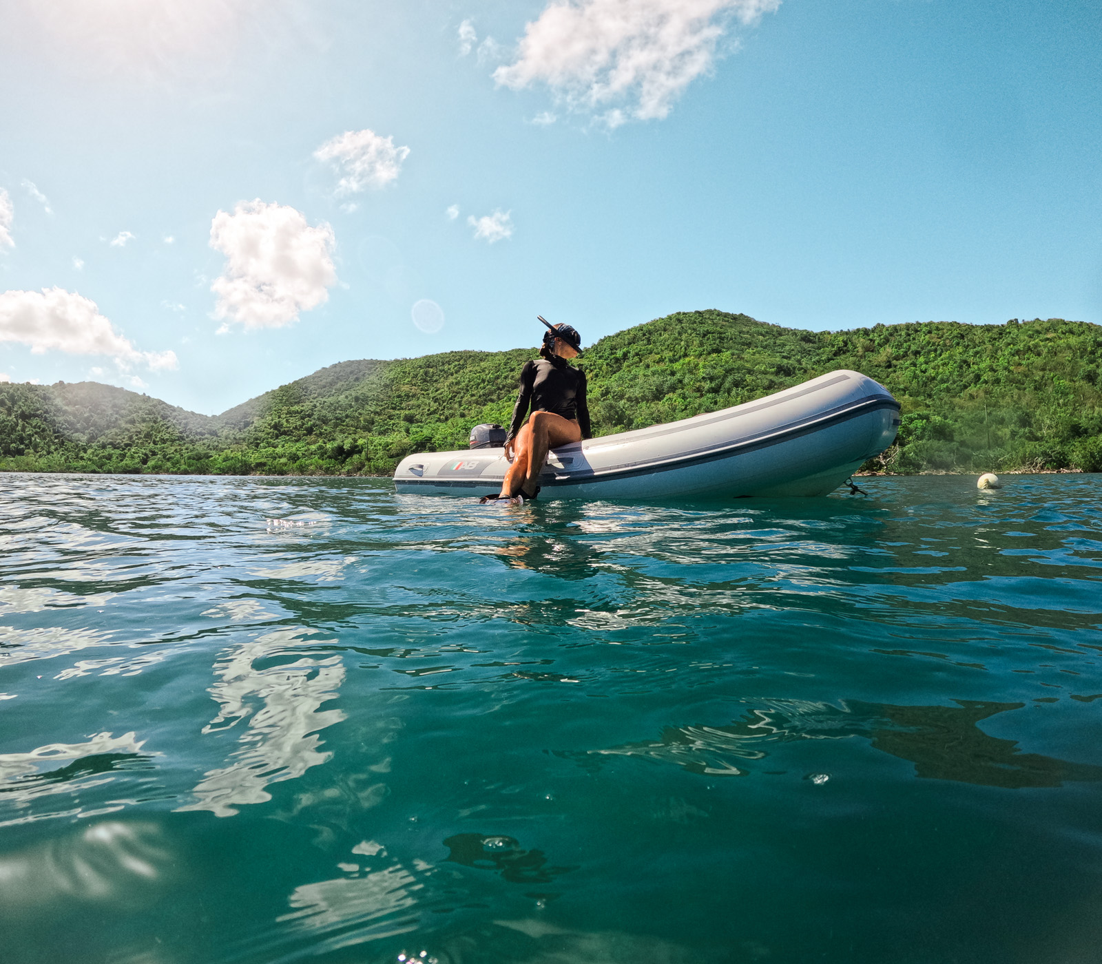 11 Very Best Things to do in St. John: Girl sitting on a dinghy with snorkel gear, tied to a mooring ball near mangroves in St. John, USVI