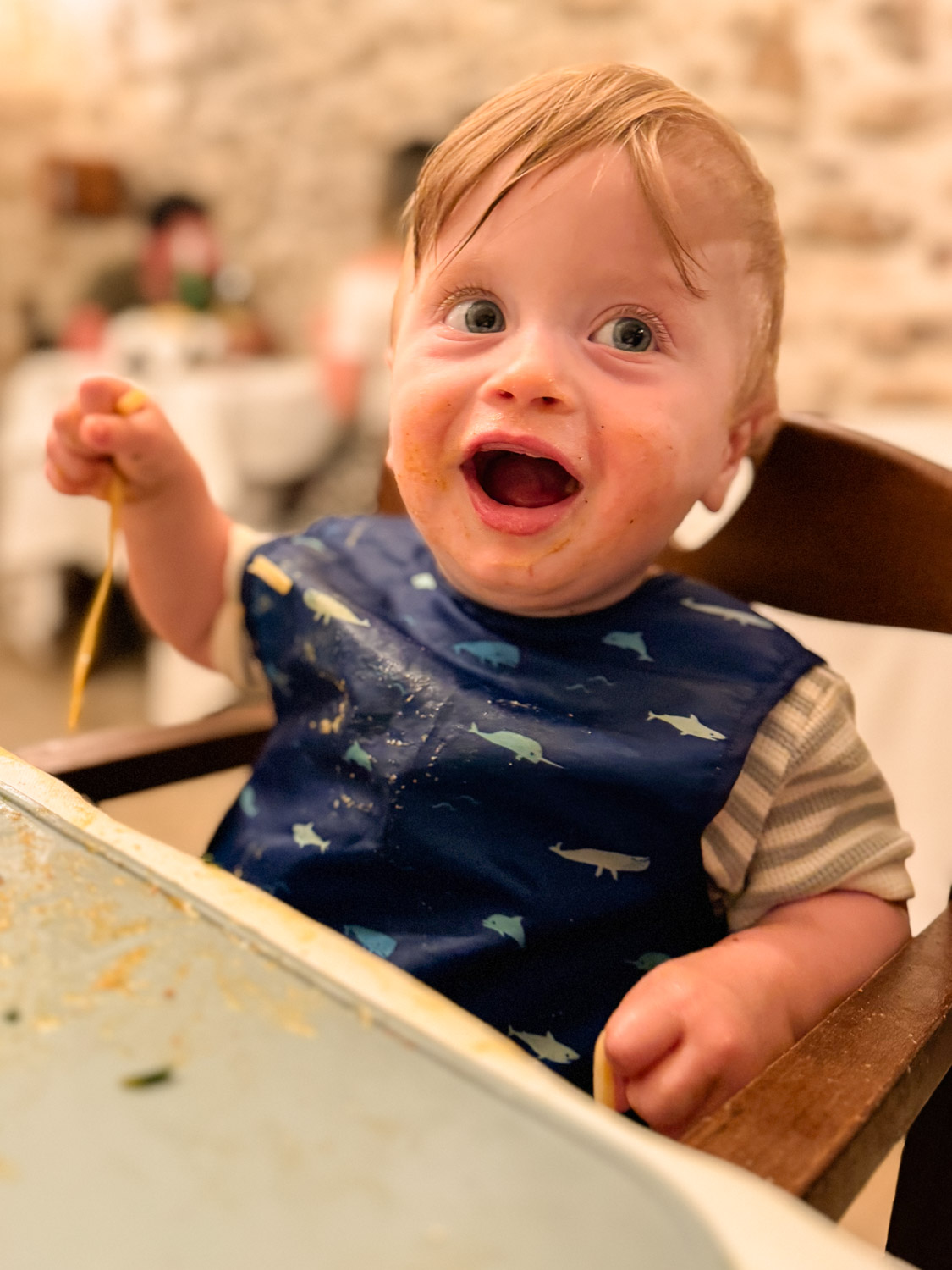 Essential Packing List for Traveling to Europe with a Baby: Baby sitting in a high chair eating spaghetti in Vieste, Puglia, Italy