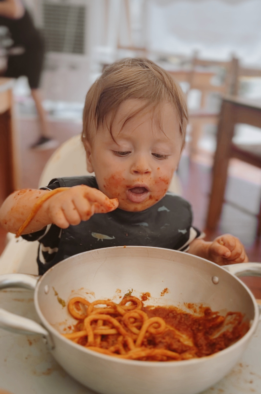 Essential Packing List for Traveling to Europe with a Baby: Baby eating spaghetti with a wipe clean bib and placemat in Monopoli, Puglia, Italy