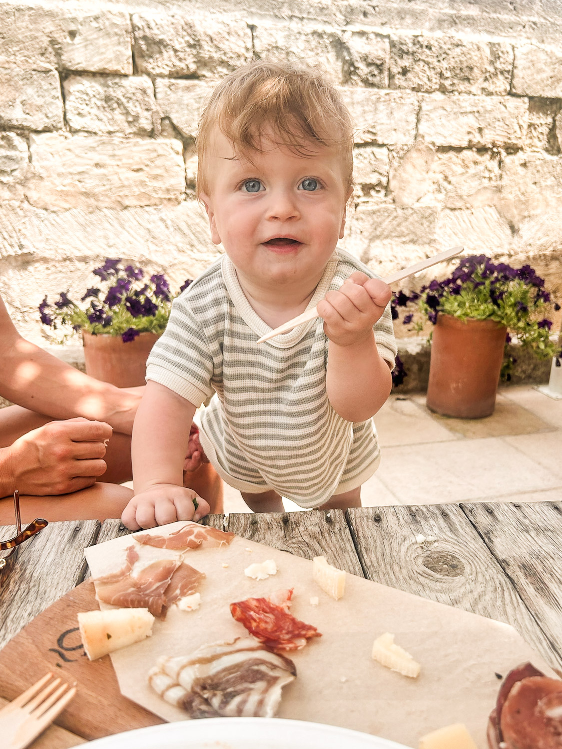 Essential Packing List for Traveling to Europe with a Baby: Baby standing on a chair at a wine bar in Otranto, Puglia, Italy