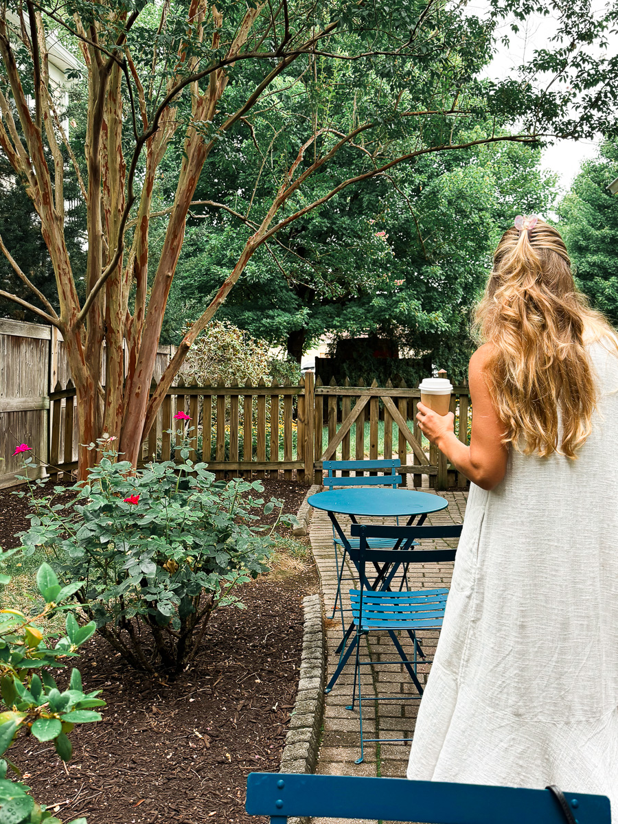 9 Must-Do Activities for the Perfect Weekend in Annapolis, Maryland: Woman standing with coffee in the backyard garden of Bakers & Co. in Annapolis, Maryland
