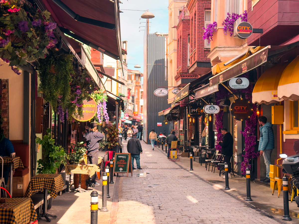 11 Best, Most Unique Things to Do in Istanbul, Turkey: A view of Breakfast Street in Besiktas, Istanbul, Turkey with colorful breakfast cafes with flowers near their entry on either side of the street.