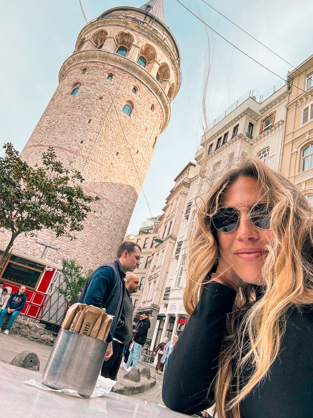 11 Best, Most Unique Things to Do in Istanbul, Turkey: A woman sitting at Viyana Kahvesi Cafe in front of the Galata Tour in Istanbul, Turkey